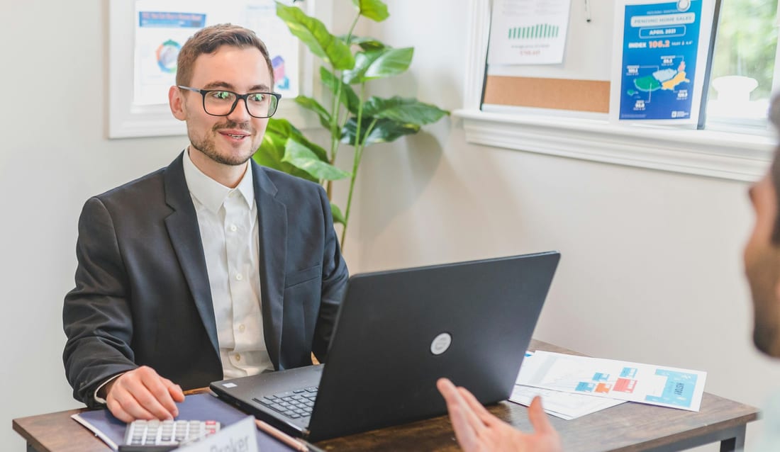 A mortgage adviser at his desk, talking a client through their options